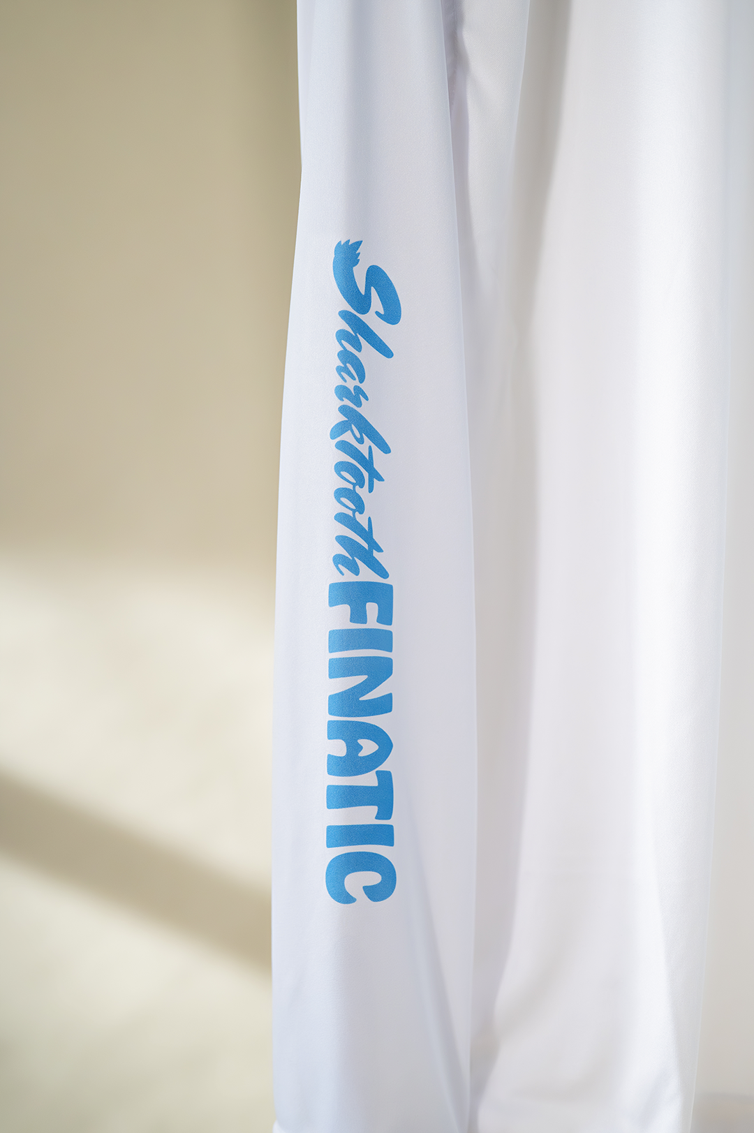 white performance long-sleeve shirt with blue logo and koi pond great white shark tooth design on the sleeve
