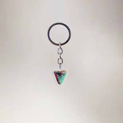 1" keychain featuring a megalodon shark in a rasta design